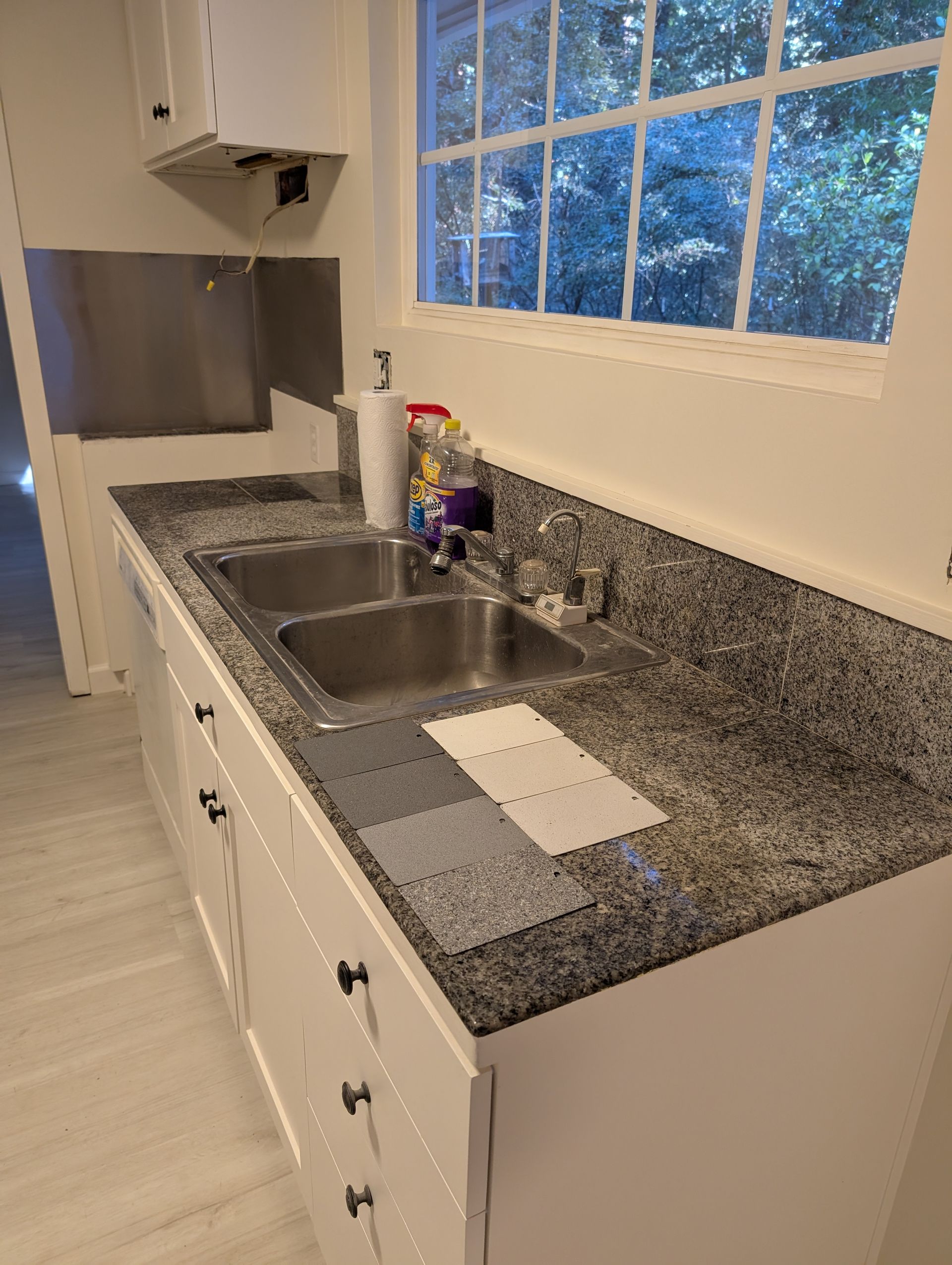 Modern kitchen with light wood cabinets, white countertops, stainless steel range hood. Modern kitchen with light wood cabinets, white countertops, stainless steel range hood.