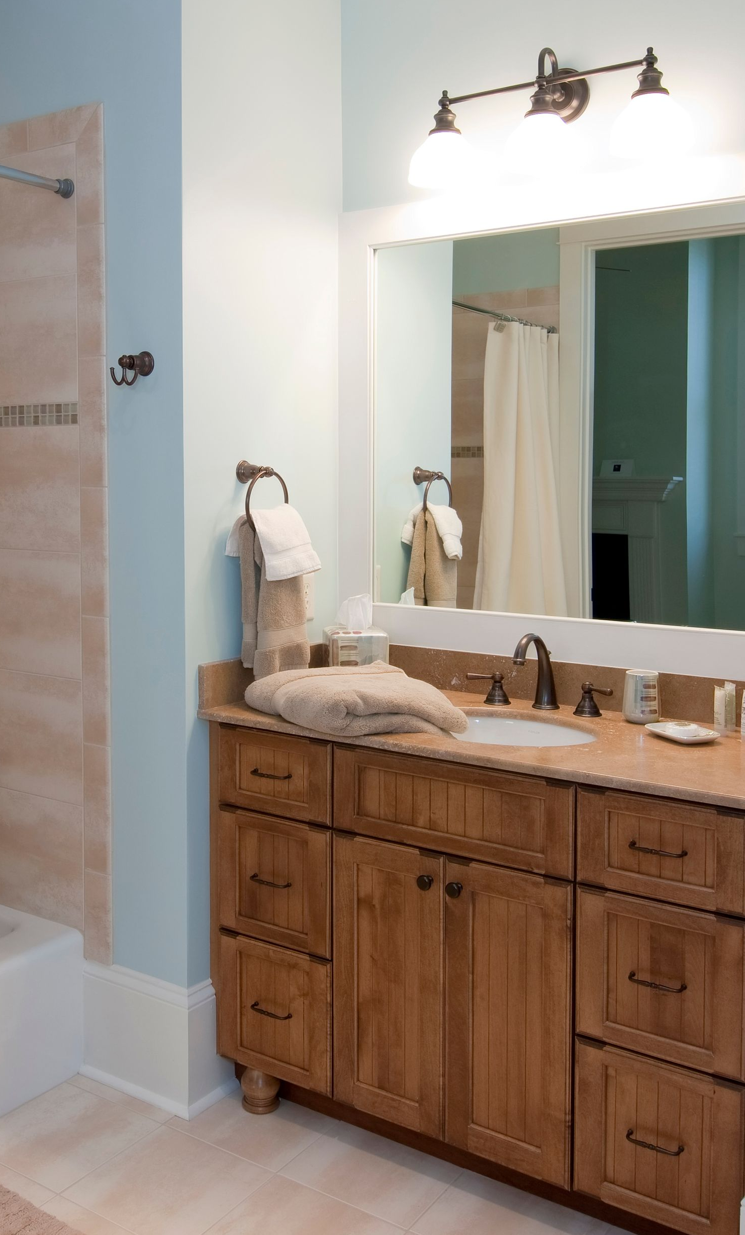 Spacious bathroom with glass shower, marble walls, and a chandelier. A standalone tub is in the background. Spacious bathroom with glass shower, marble walls, and a chandelier. A standalone tub is in the background.