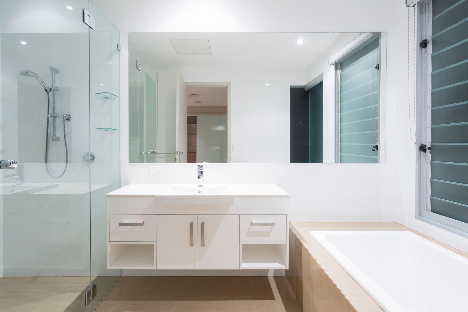 Modern white bathroom with shower, vanity, mirror, and bathtub.