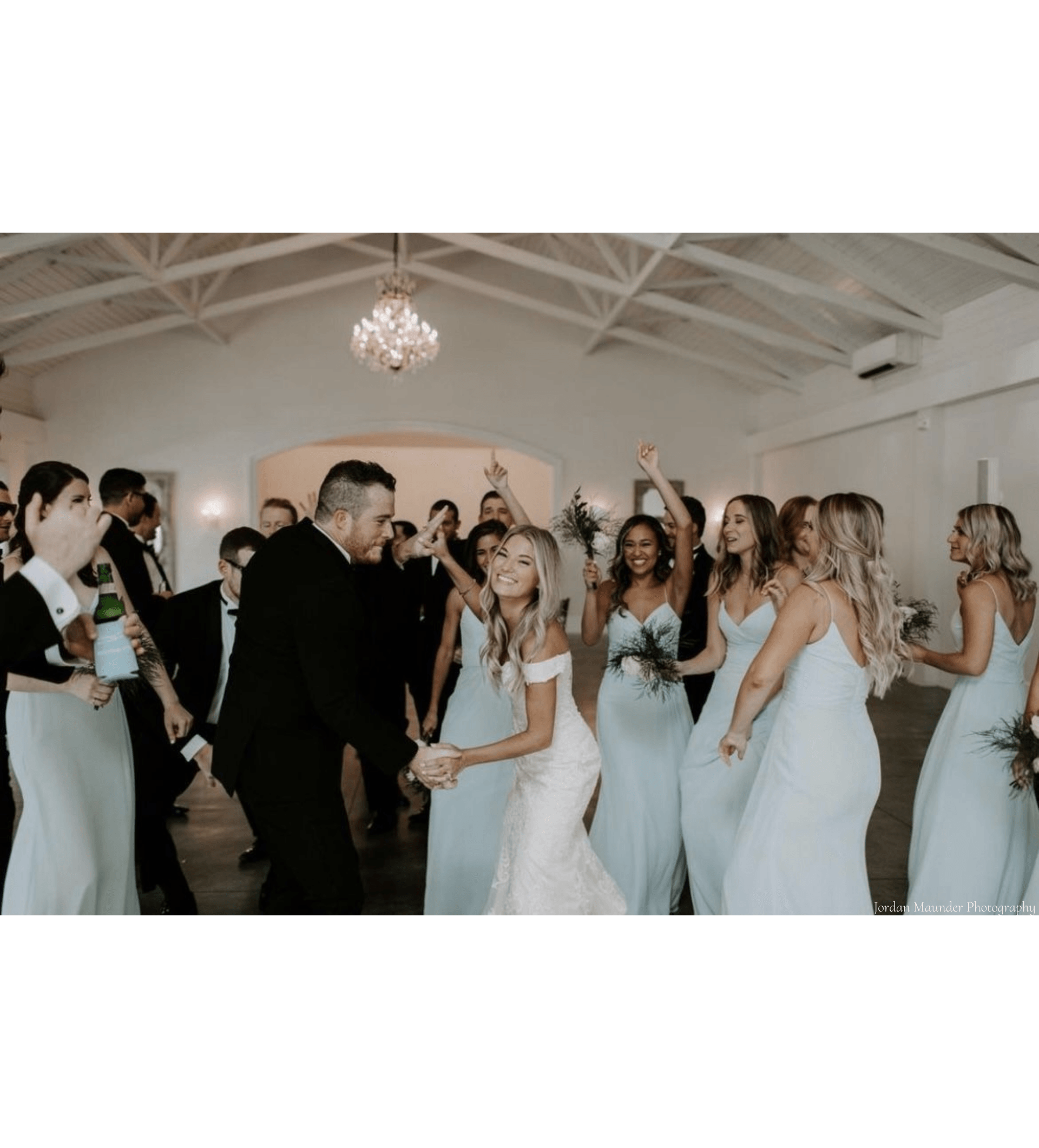 A bride and groom are celebrating with their wedding party after their wedding ceremony inside of a building.