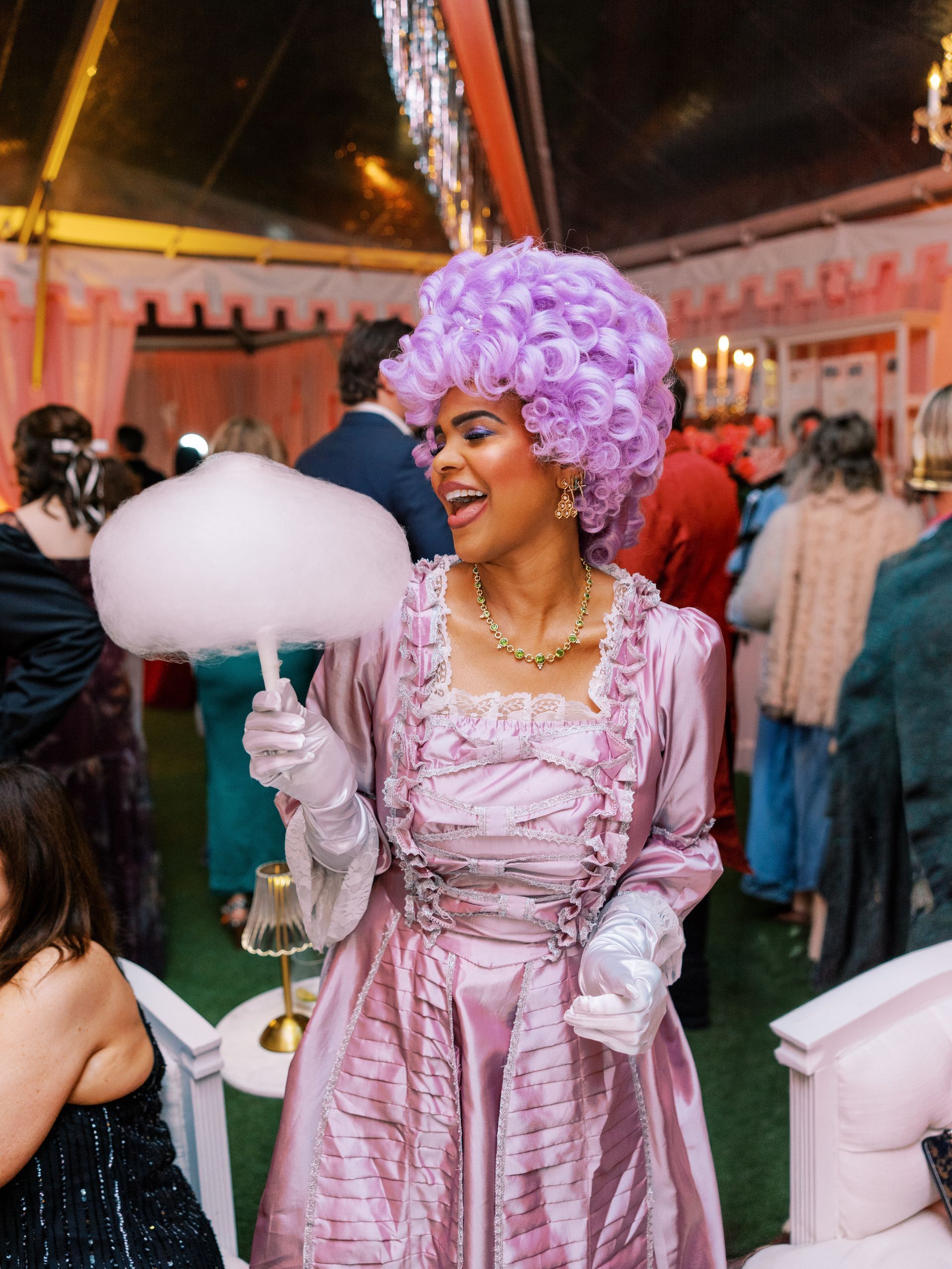 Four women in colorful outfits hold a large check at a festive nighttime celebration of An Evening To Ignite at Merrimon-Wynne in Raleigh, NC.