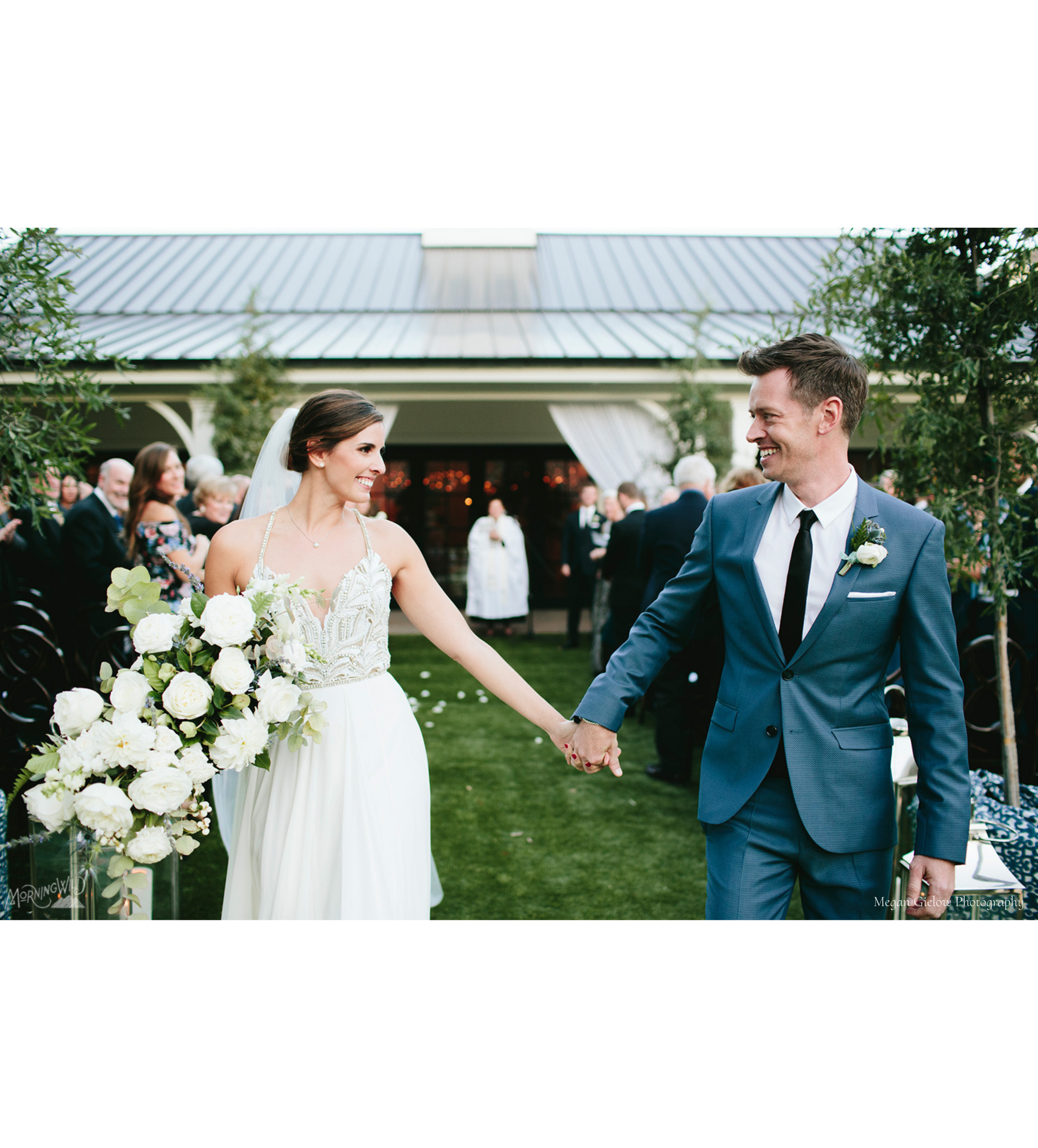 A bride and groom are walking down the aisle holding hands, smiling at each other after they just finished saying I do.