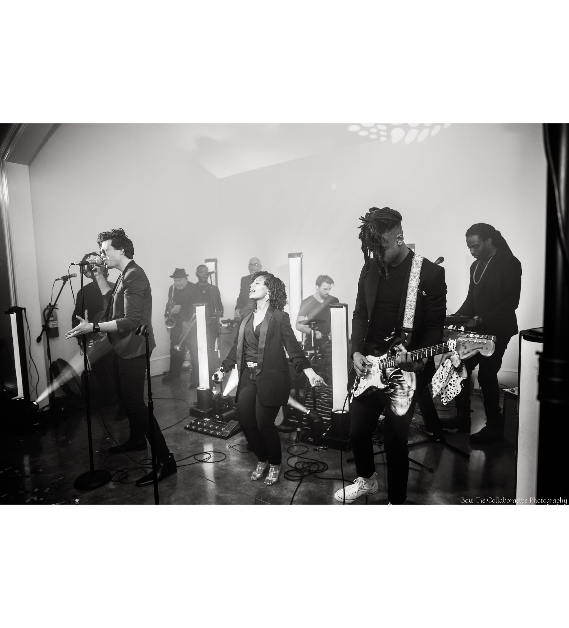 A black and white photo of a group of people playing instruments on a stage for a wedding reception.