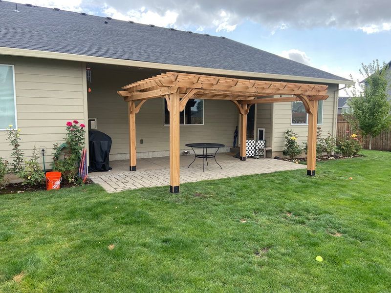 There is a pergola in the backyard of a house.