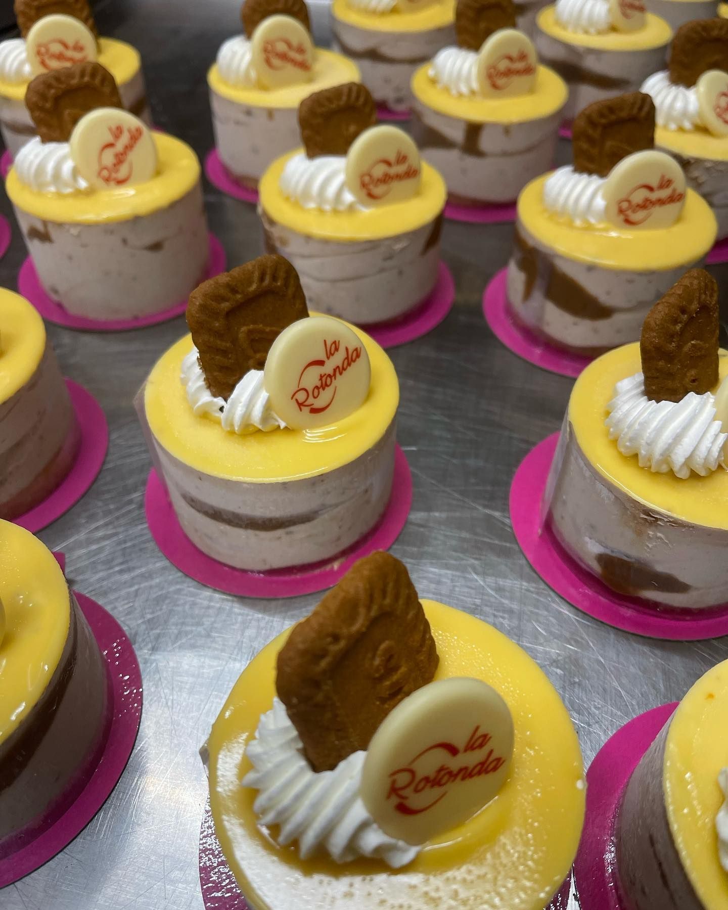 Piccole tortine al limone ricoperte di panna, biscotti e logo su sottobicchieri rosa.