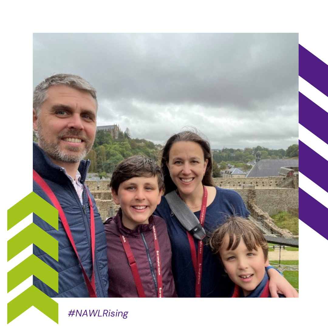 A family stands in front of a cloudy sky and town.