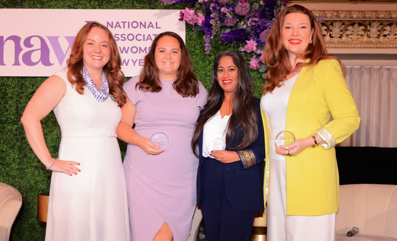 Four people smiling and holding awards.
