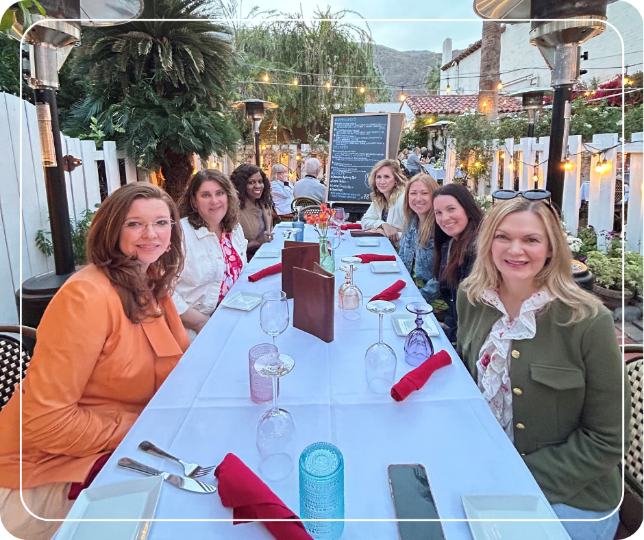 Women seated around a dinner table outside.