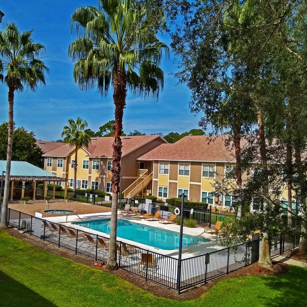 a large swimming pool surrounded by palm trees in front of a building