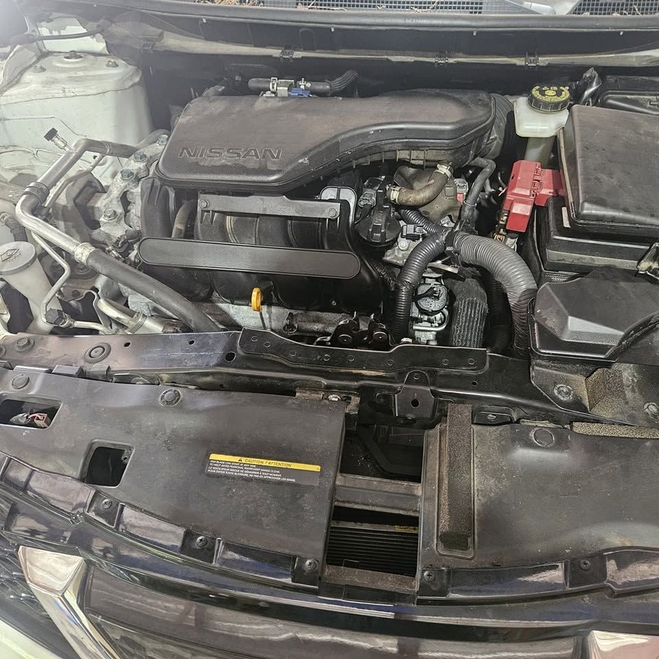 Car engine bay with the hood open, showing the engine and a disconnected front panel.