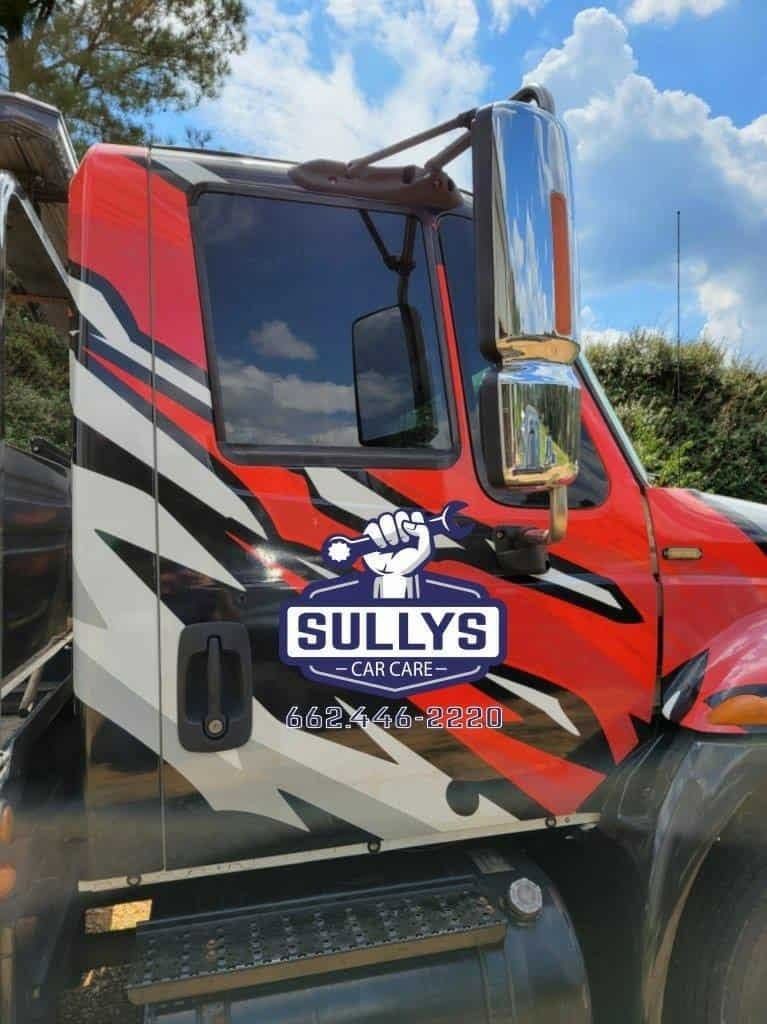 Red Sully’s trucking company semi cab with bold black, white, and red graphics under a blue sky