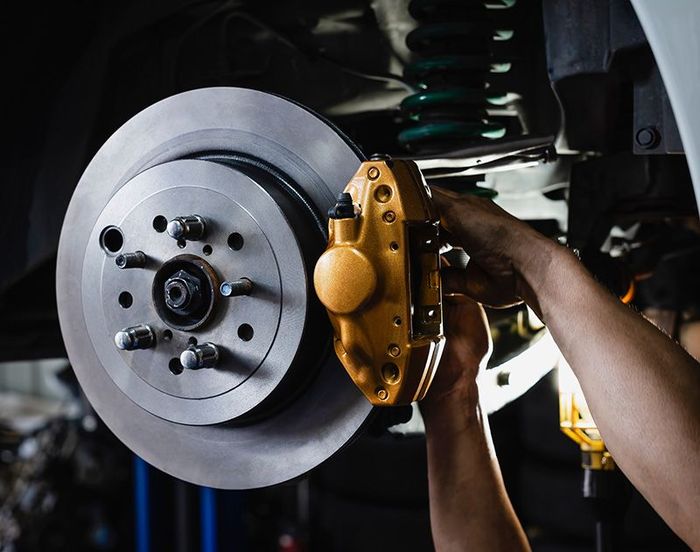 A person is fixing a brake on a car in a garage.