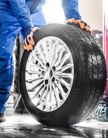 A man is holding a tire in his hands in a garage.