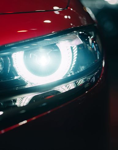 A close up of a red car 's headlight at night.