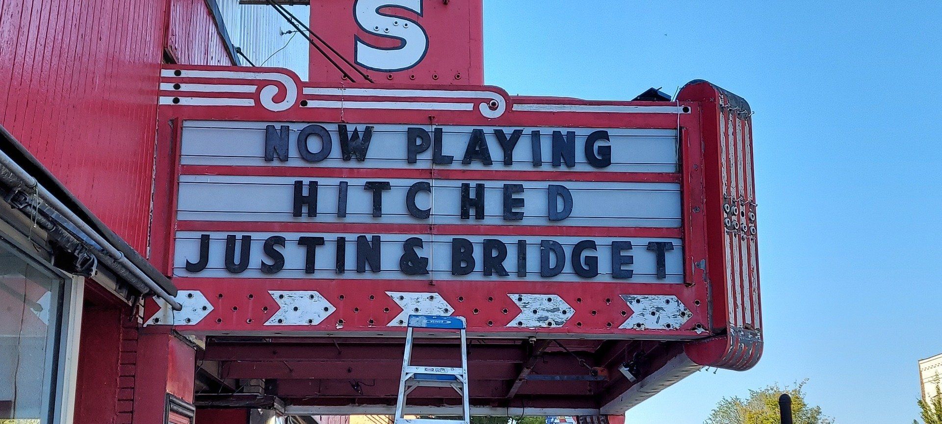 A red sign that says now playing hitched justin bridget