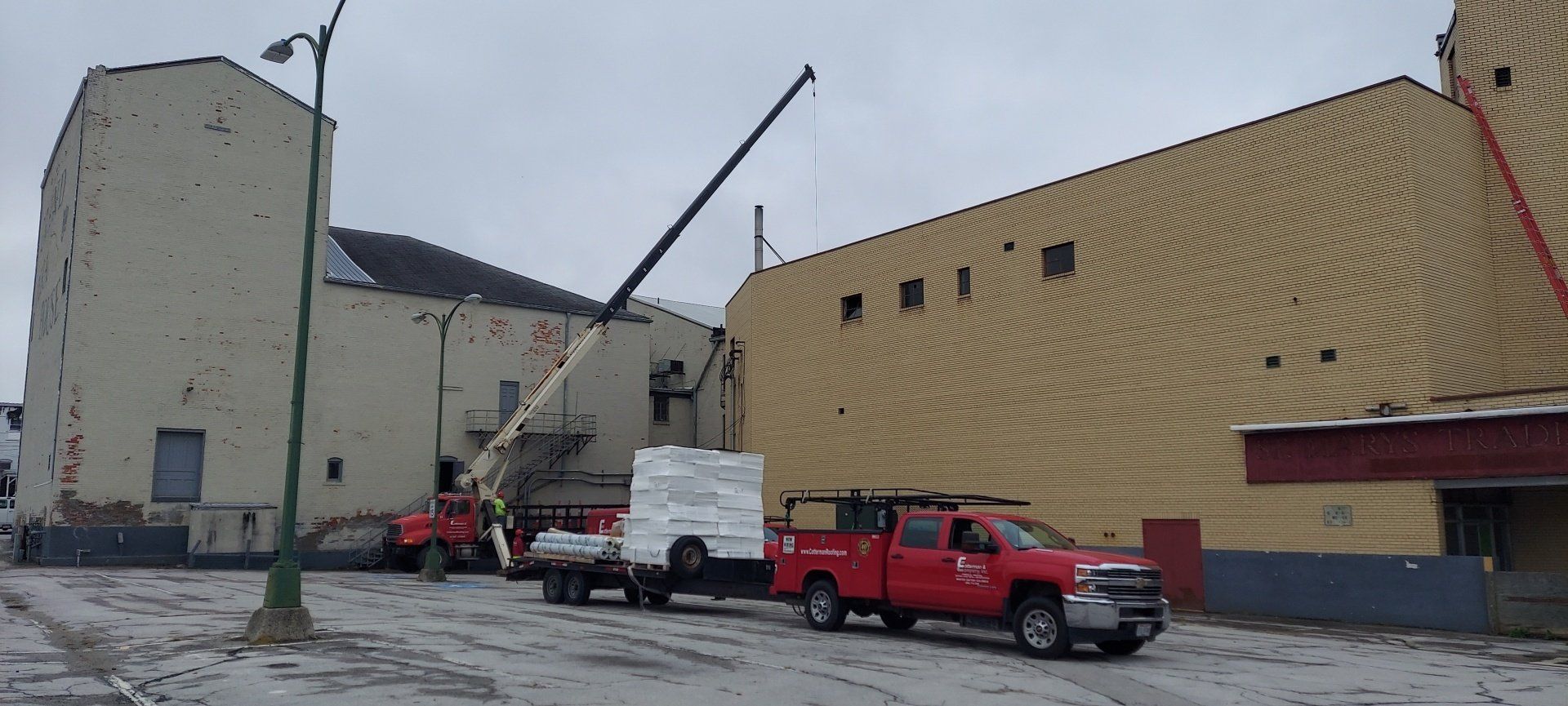Two red trucks are parked in front of a large building.