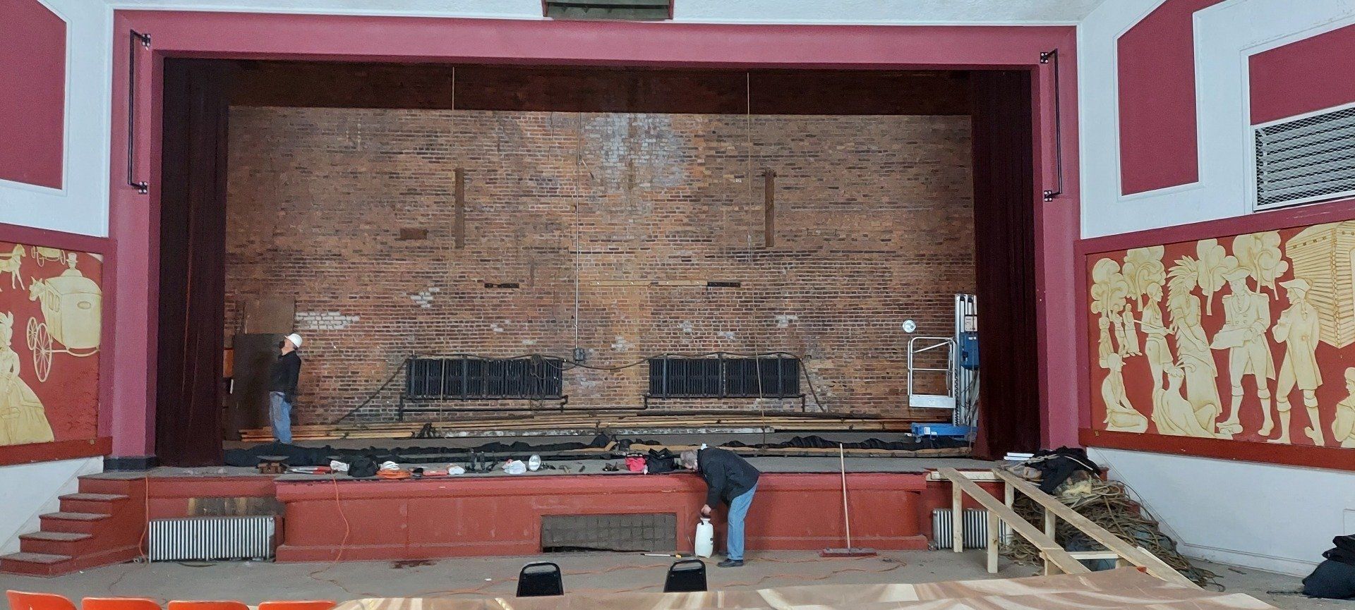 A man is standing in front of a stage in an auditorium.