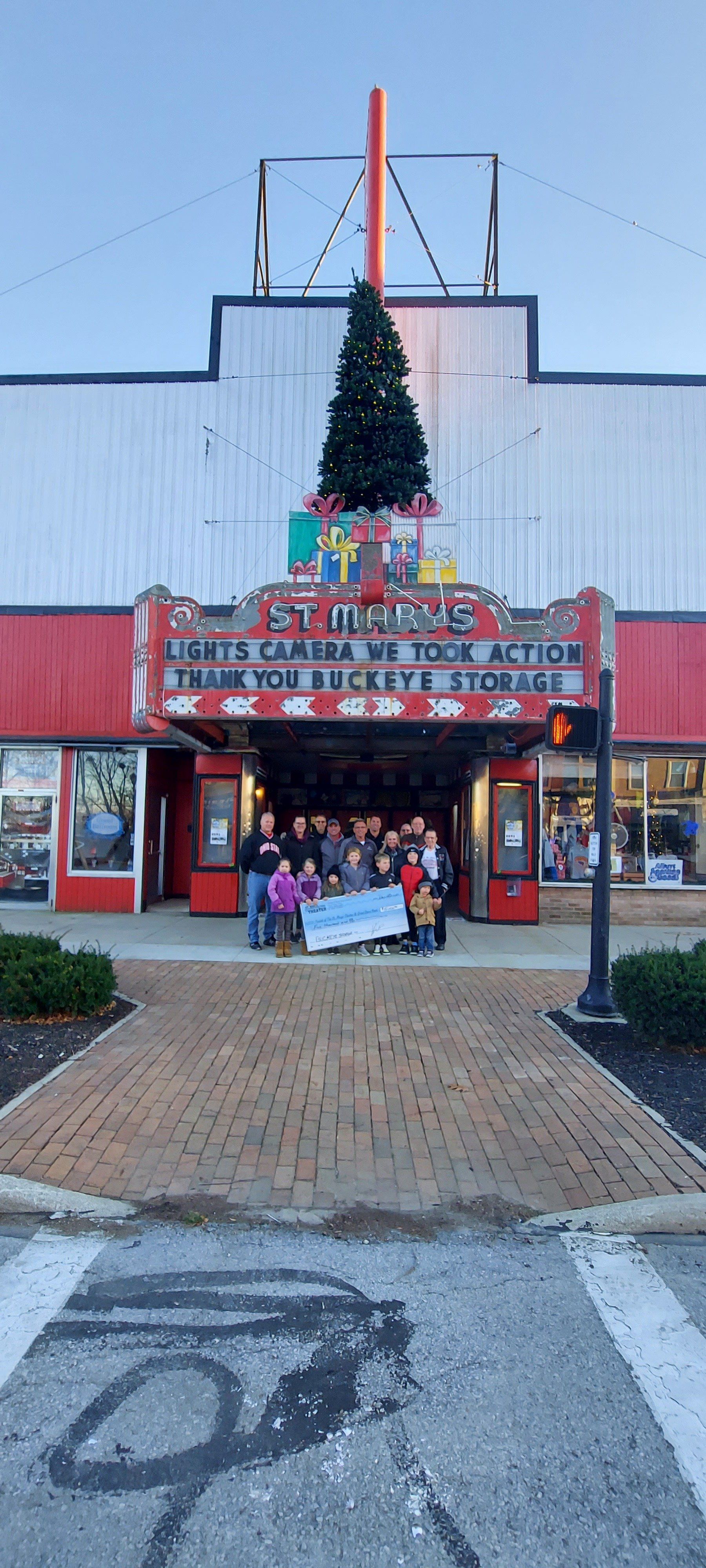 A group of people are standing in front of a building with a christmas tree on top of it.