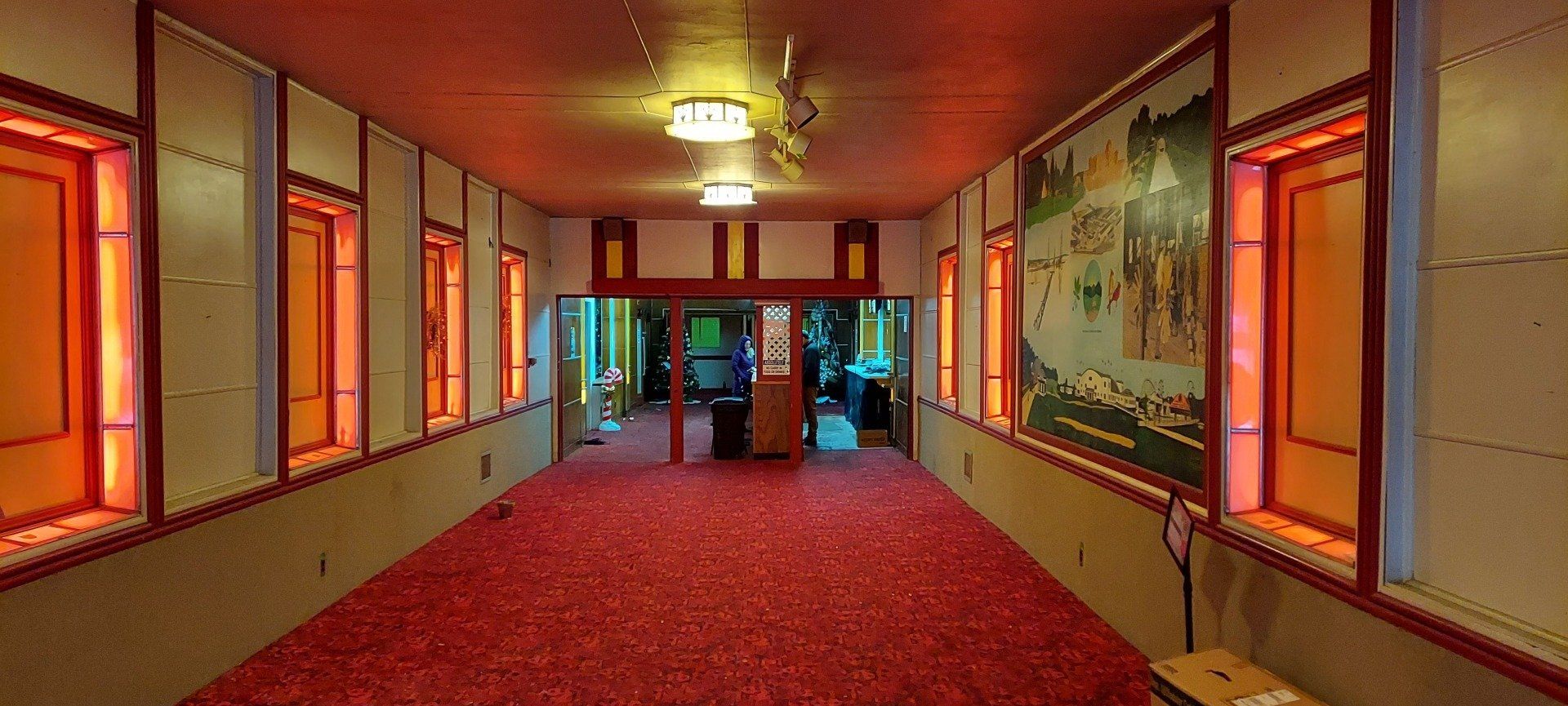 A long hallway with a red carpet and a painting on the wall.