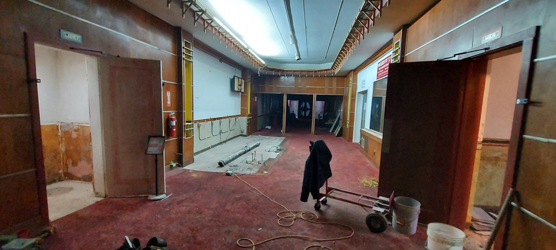 A large empty room with a red carpet and wooden walls.