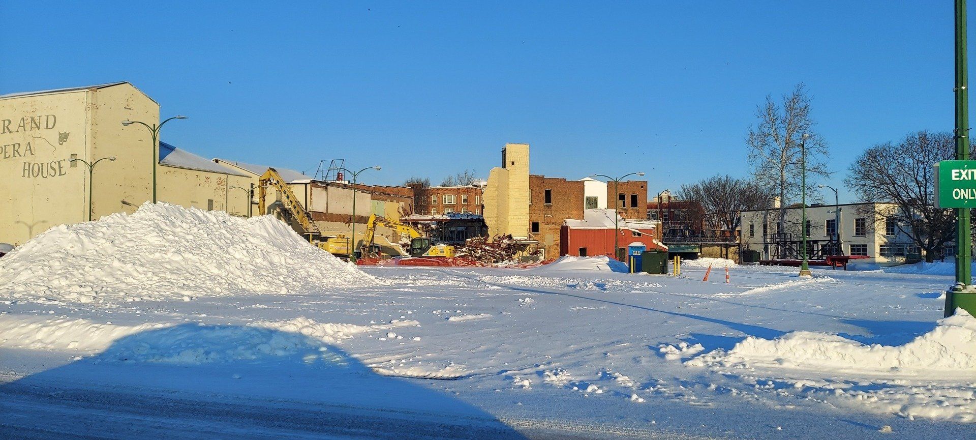 A snowy parking lot with a green exit sign in the foreground
