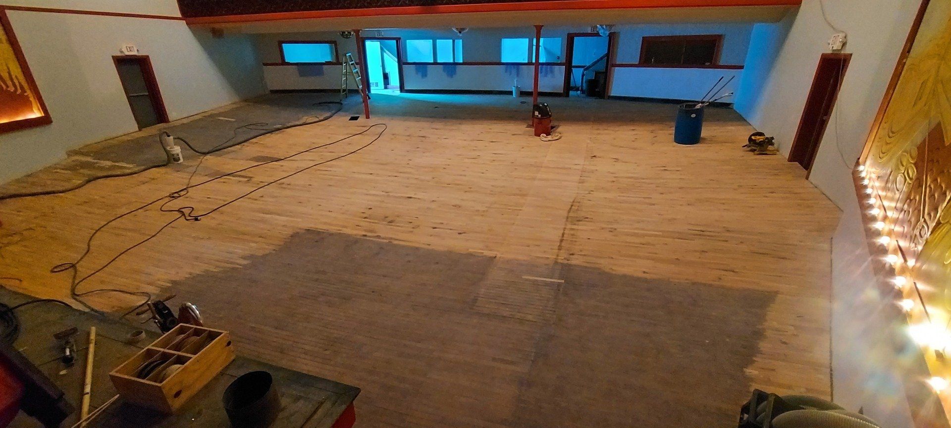 A large room with a wooden floor is being remodeled.