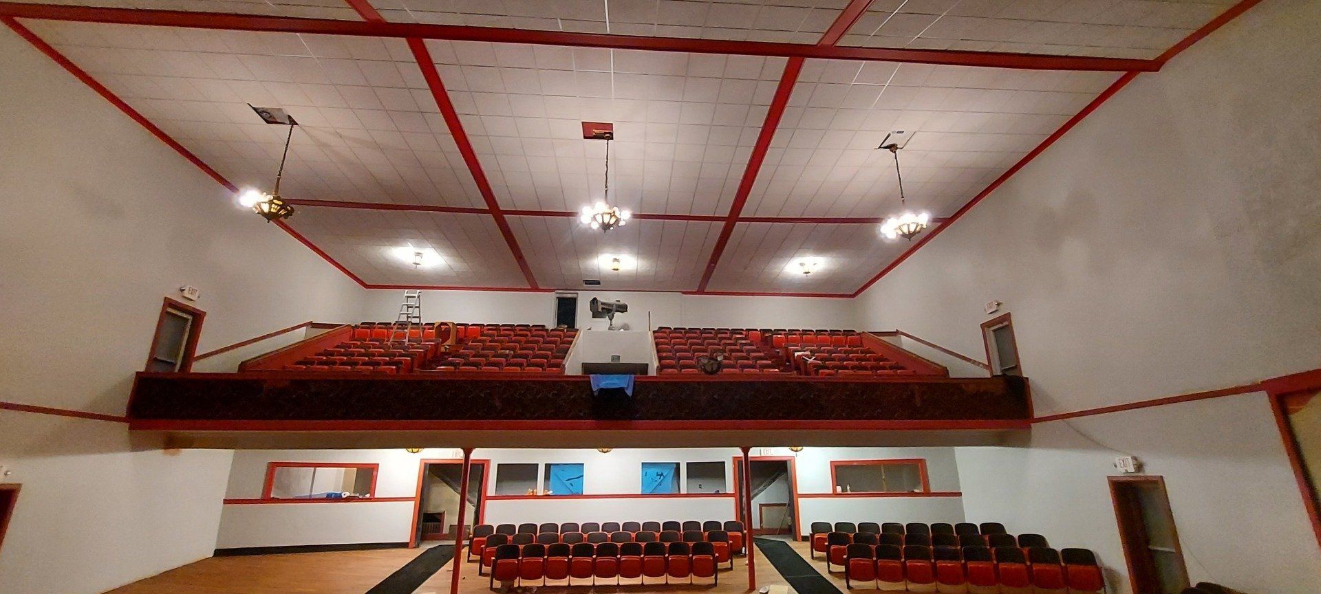 A large auditorium with red seats and a balcony.