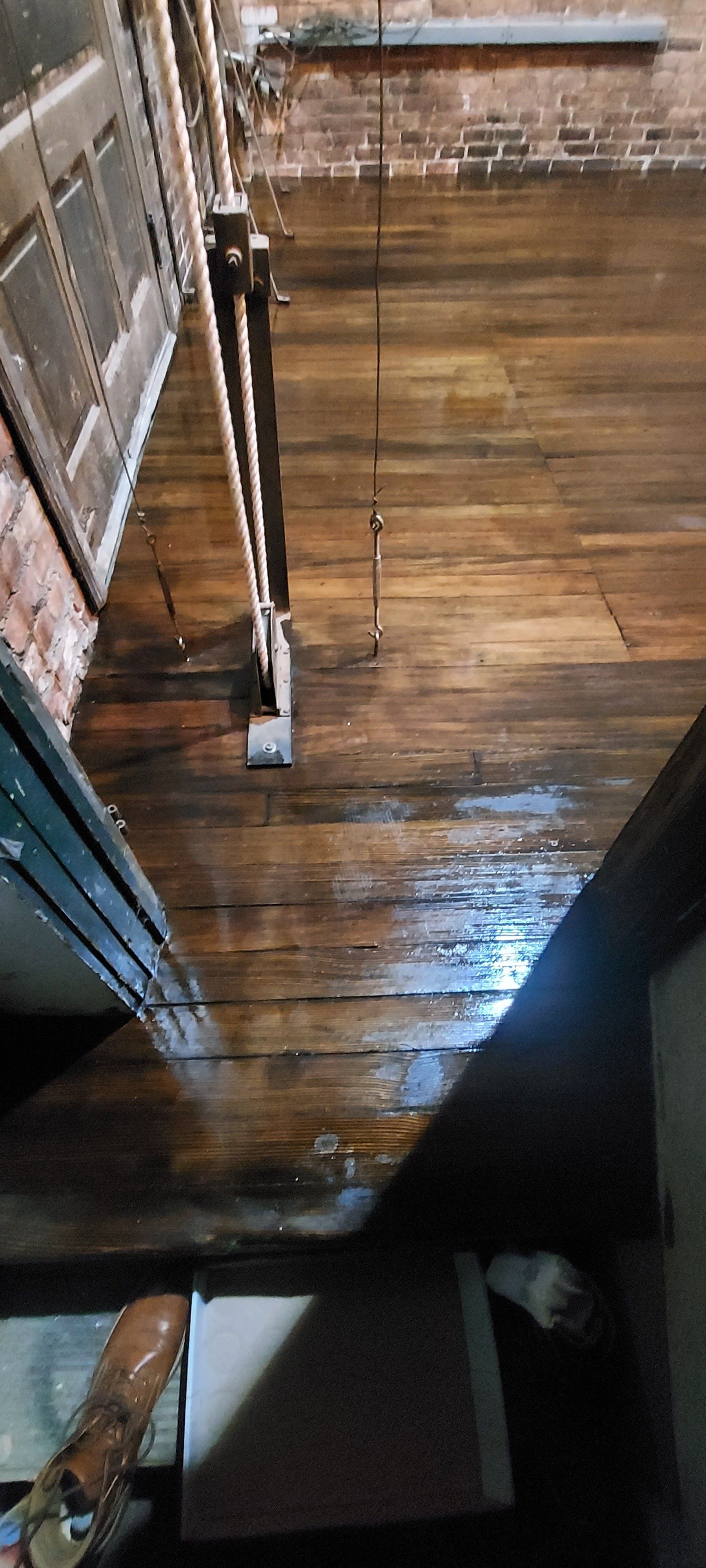 A wooden floor in a room with stairs and a brick wall.