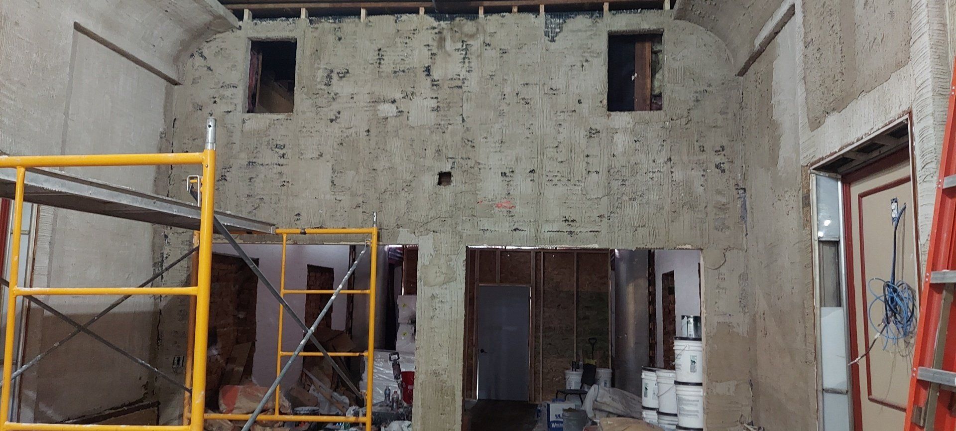 A building under construction with scaffolding and a ladder.