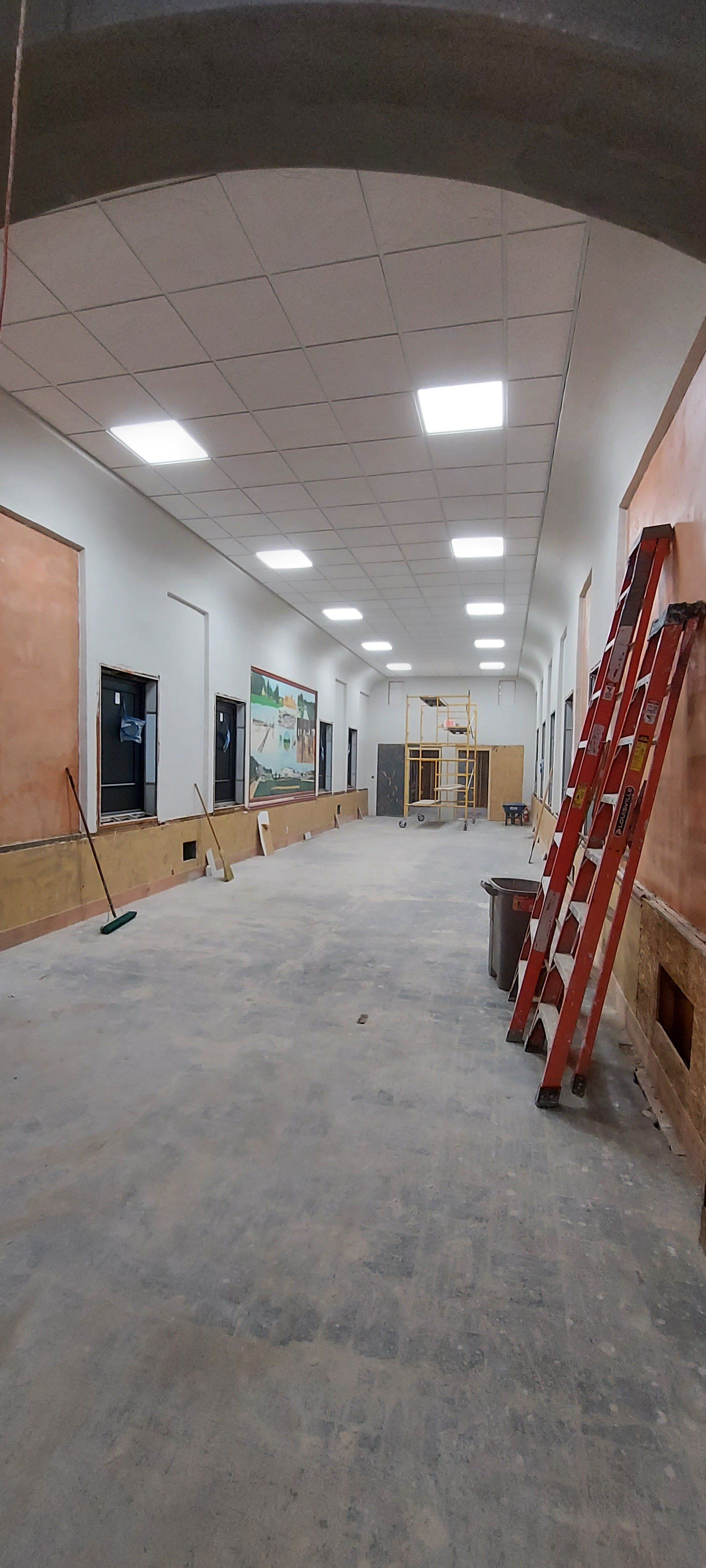 A large empty room with a ladder in the middle of it.