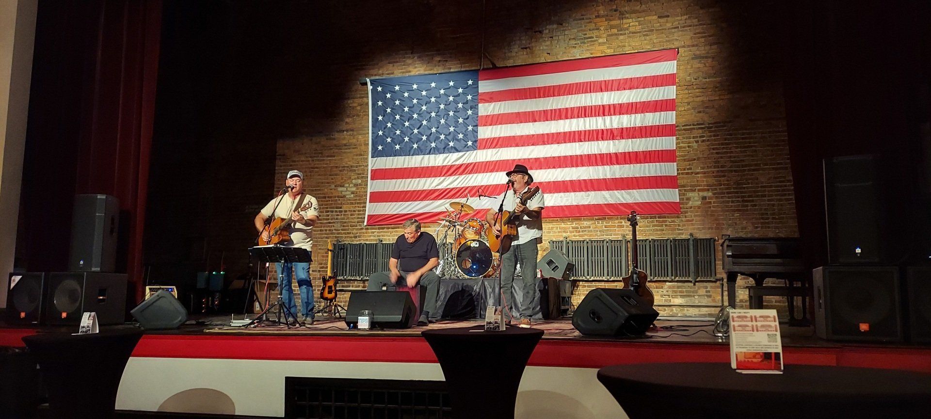 A band is playing on a stage in front of an american flag.