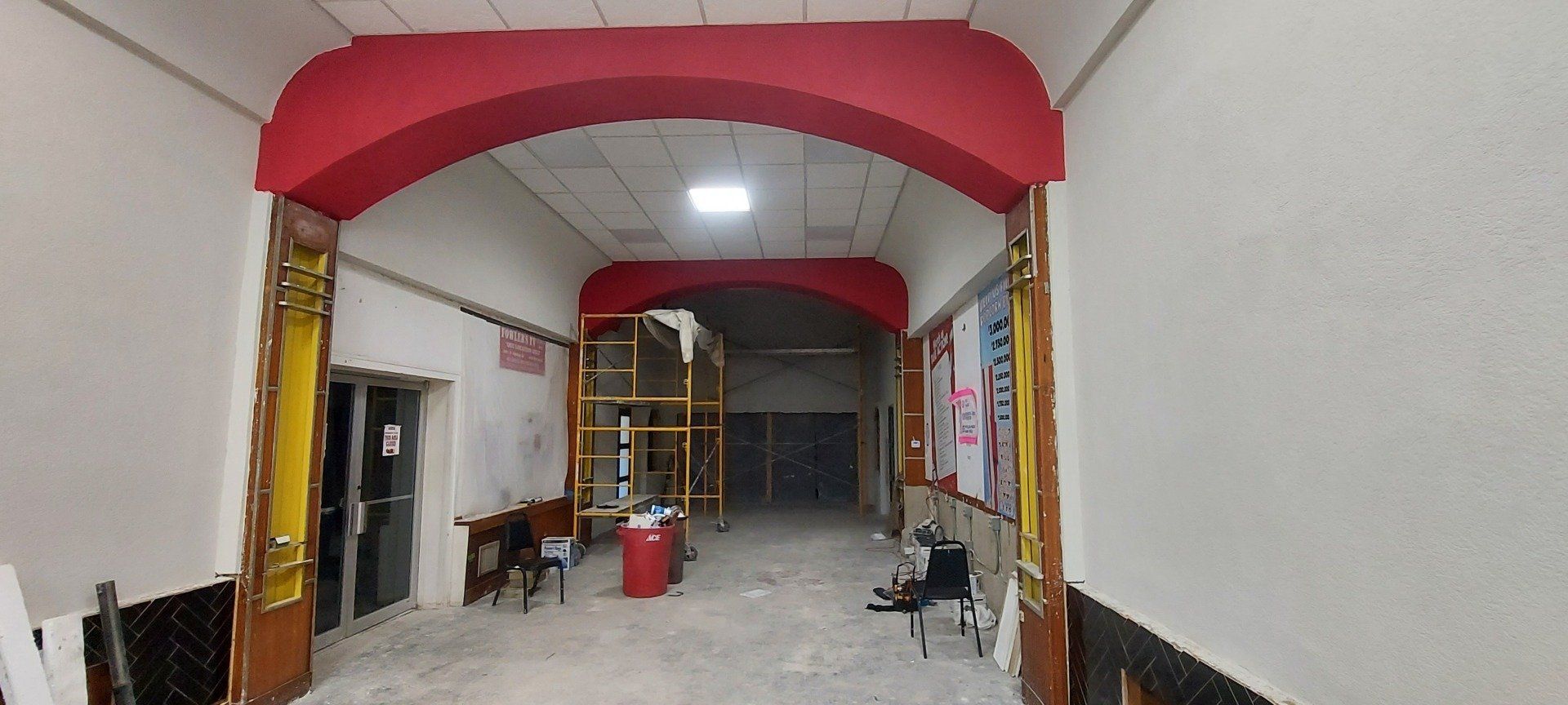 A long hallway with a red arch in the middle of it.