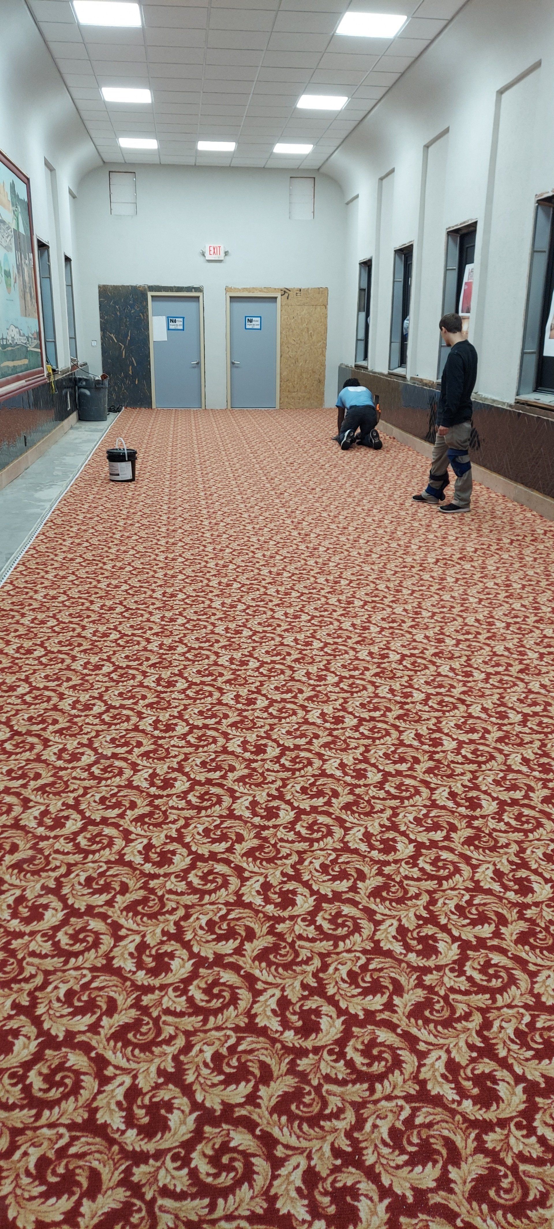 A man is cleaning a large room with a vacuum cleaner.