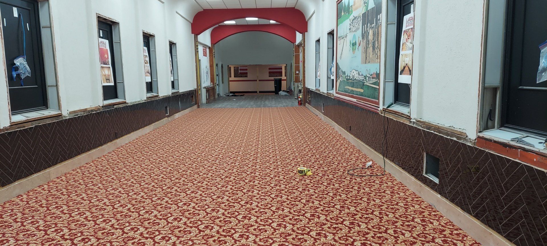 A long hallway with a red carpet and a red archway.