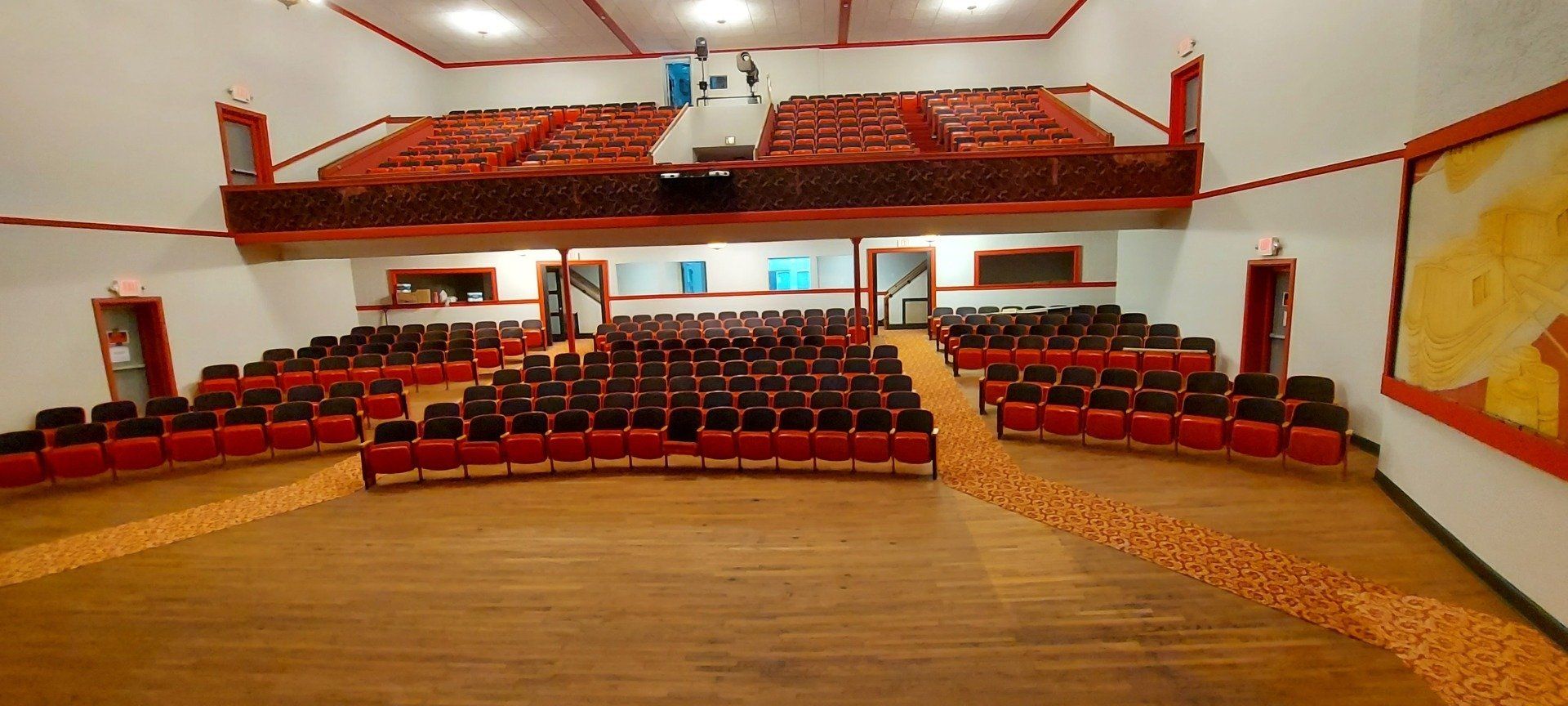 A large auditorium with rows of red seats and a balcony.