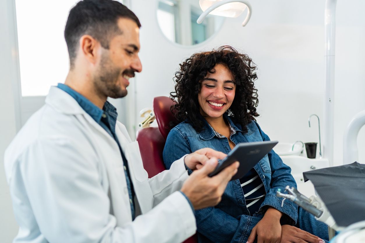 Dentist showing a tablet to a smiling patient in a dental chair