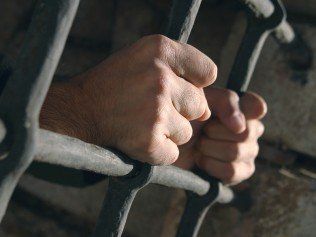 hands-grabbing-prison-bars