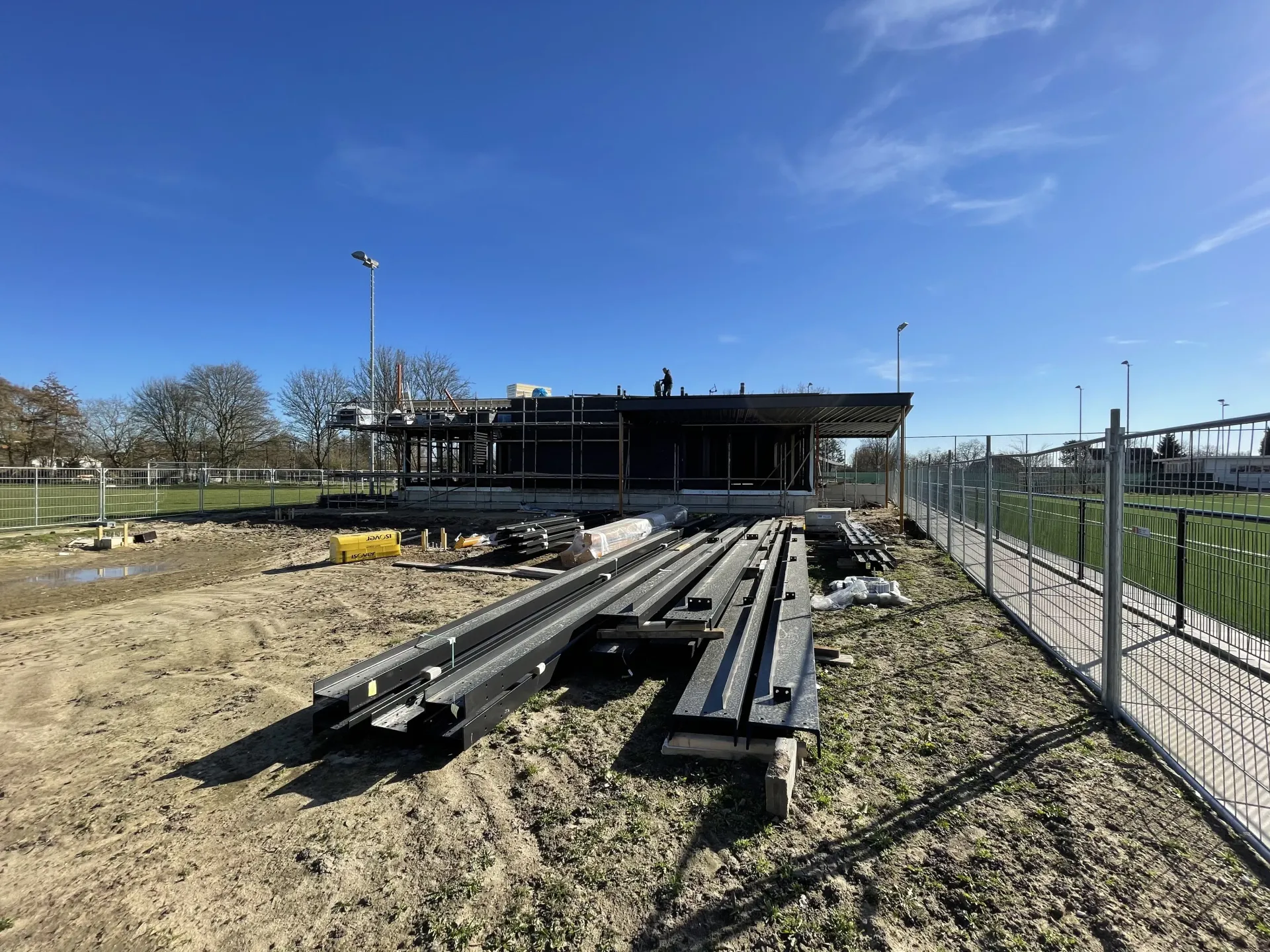 In een veld naast een hek wordt een huis gebouwd. Door Willems Boven-Leeuwen.