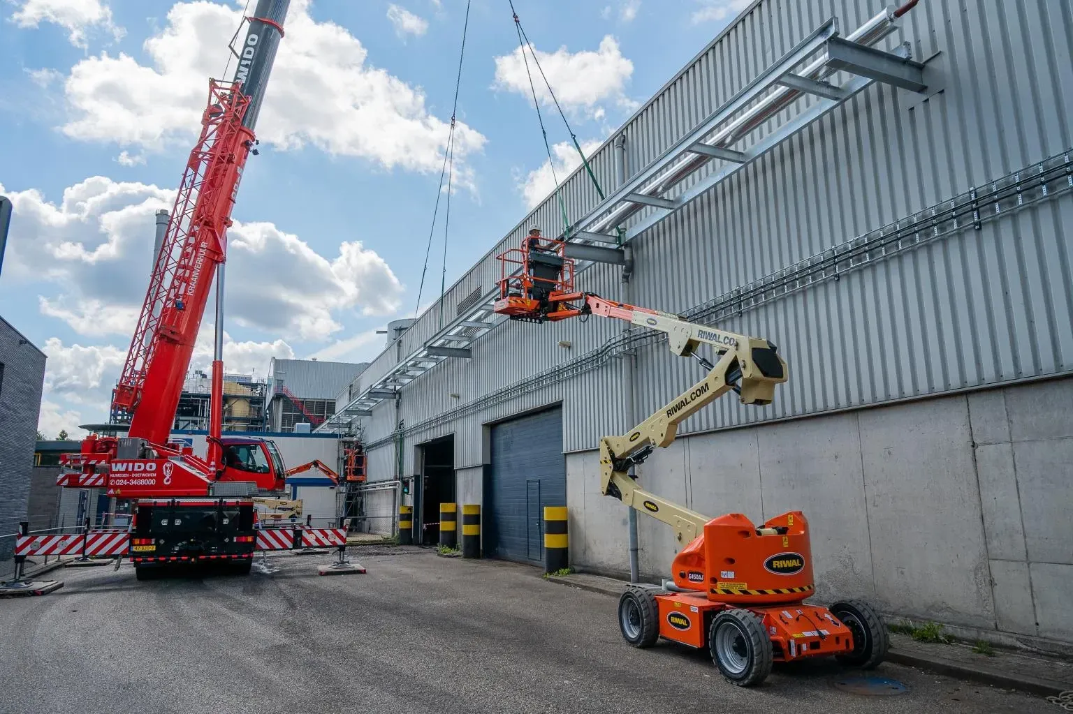 Een kraan en een jlg-lift werken aan een gebouw. Door Willems Boven-Leeuwen.