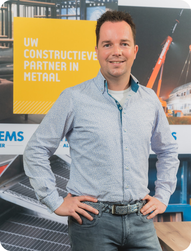 Een man staat met zijn handen op zijn heupen voor een bord met de tekst uw partner in metaal Marcel van der Wielen