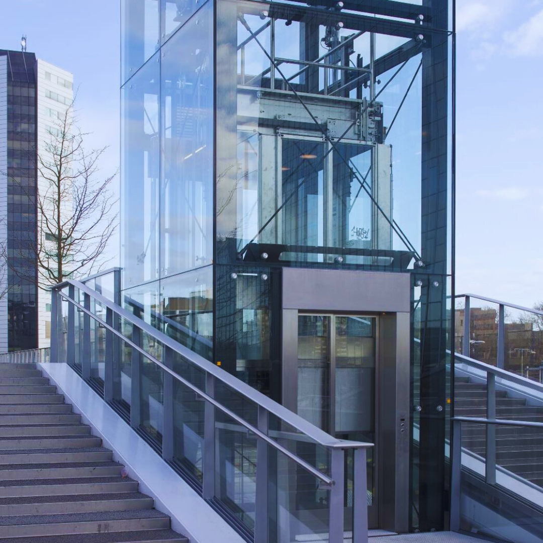Een glazen lift met trappen ernaartoe Door Willems Boven-Leeuwen.