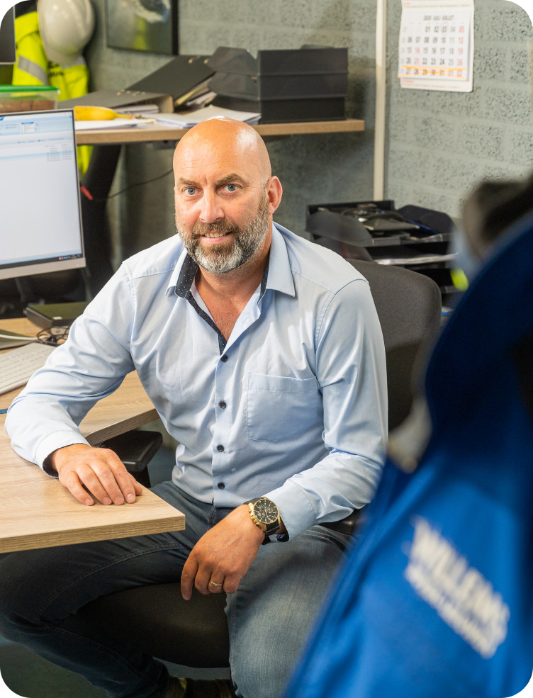 Een man met een baard zit aan een bureau achter een computer. Dries Dobbelstein