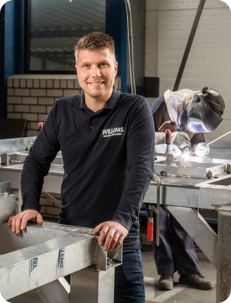 Een man in een blauw shirt staat voor een lasapparaat. Jimmy van Leeuwen