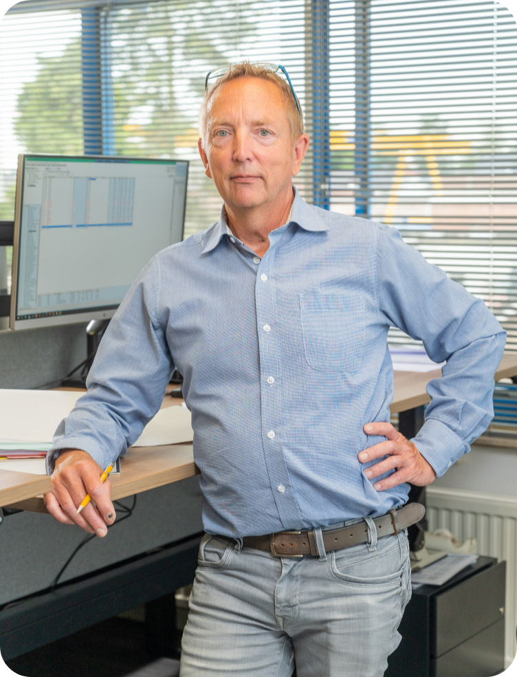 Een man staat voor een bureau met zijn handen op zijn heupen. Robert Jonkheid