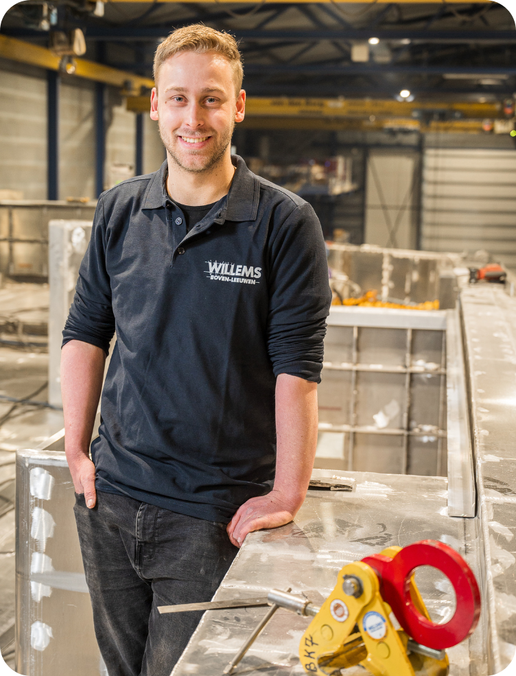 Een man leunt op een tafel in een fabriek. Wim van Dinther.