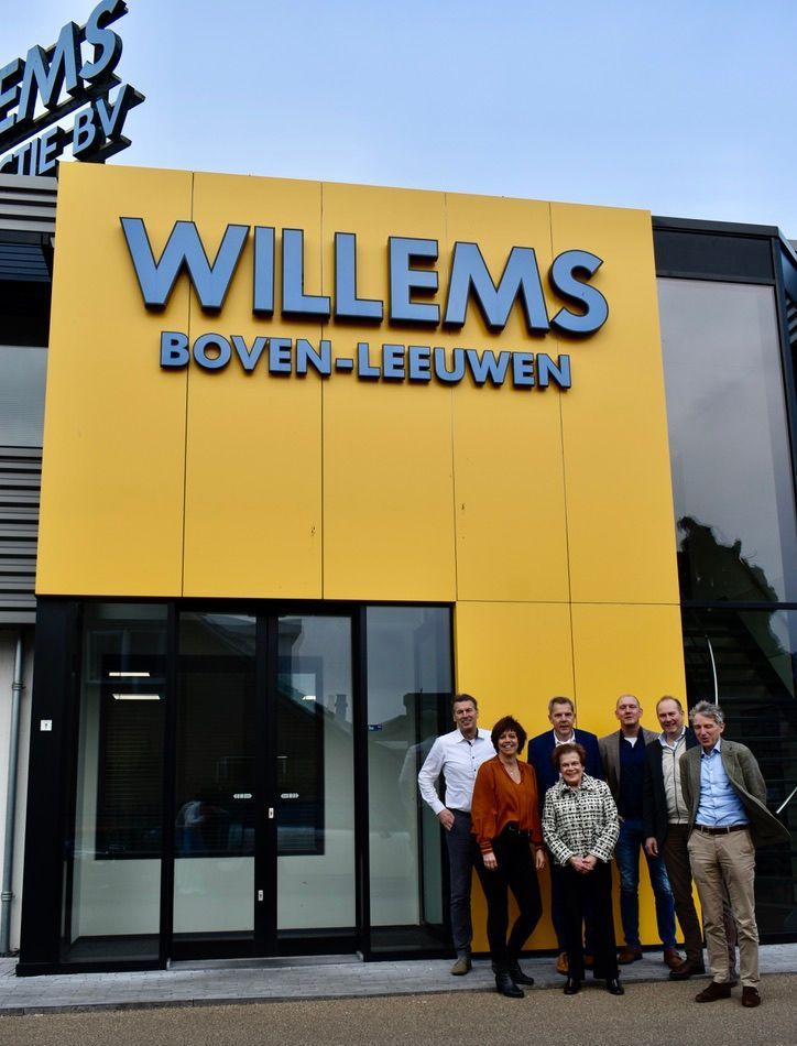 Een groep mensen staat voor een Willemsgebouw