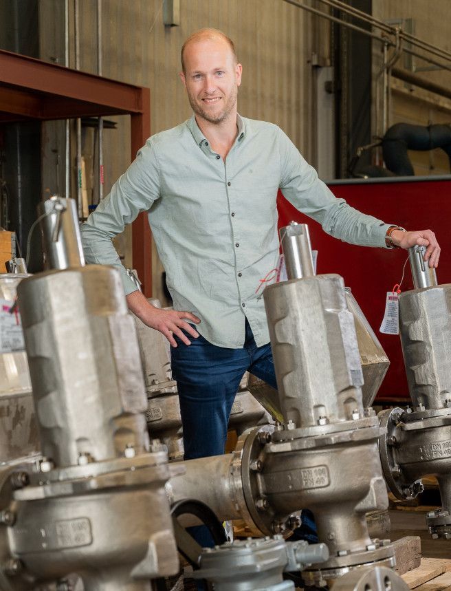 Een man staat voor een rij kleppen in een fabriek. Dirk Boekhorst.