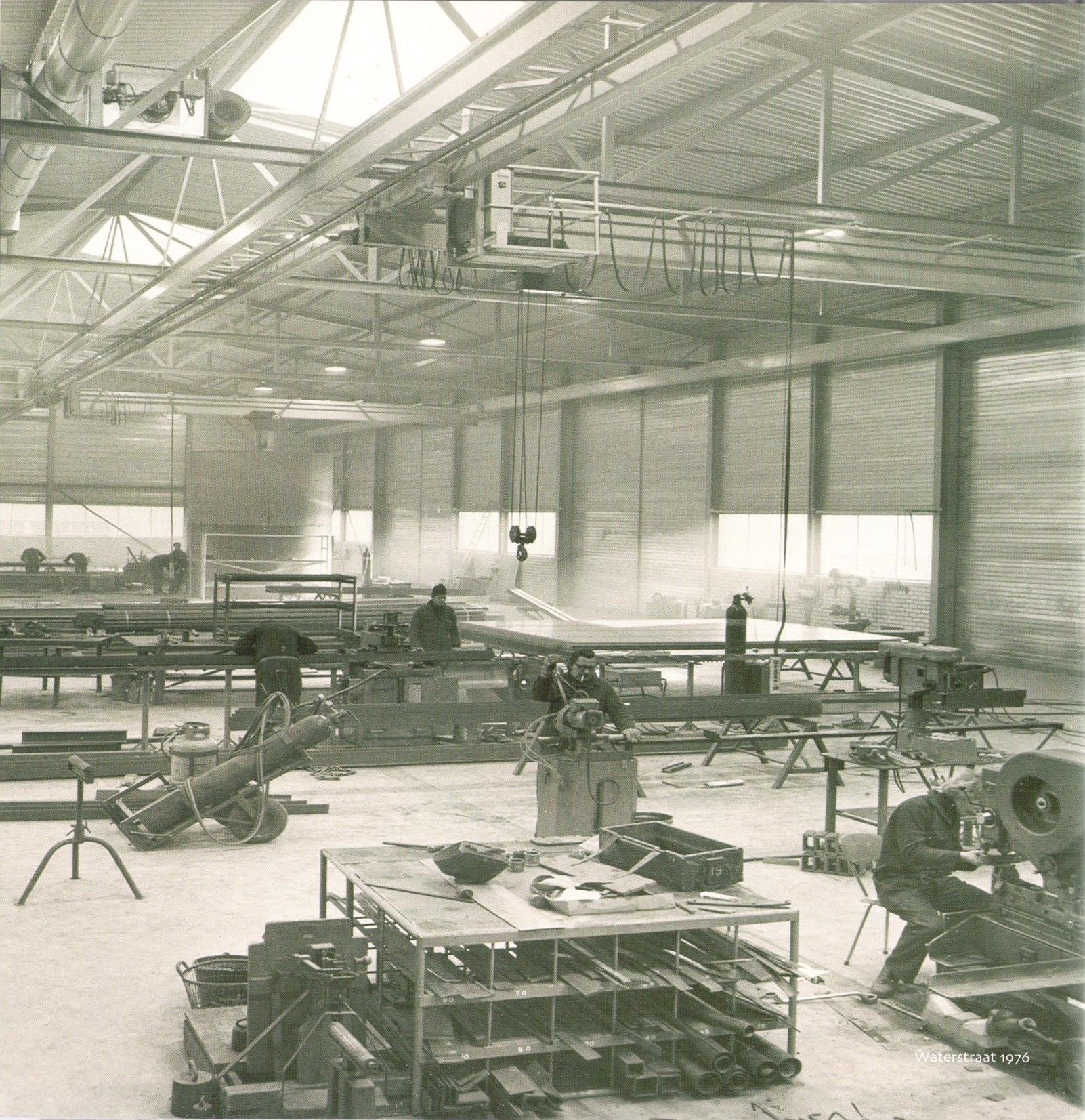 Een zwart-witfoto van een fabriek met een paar arbeiders