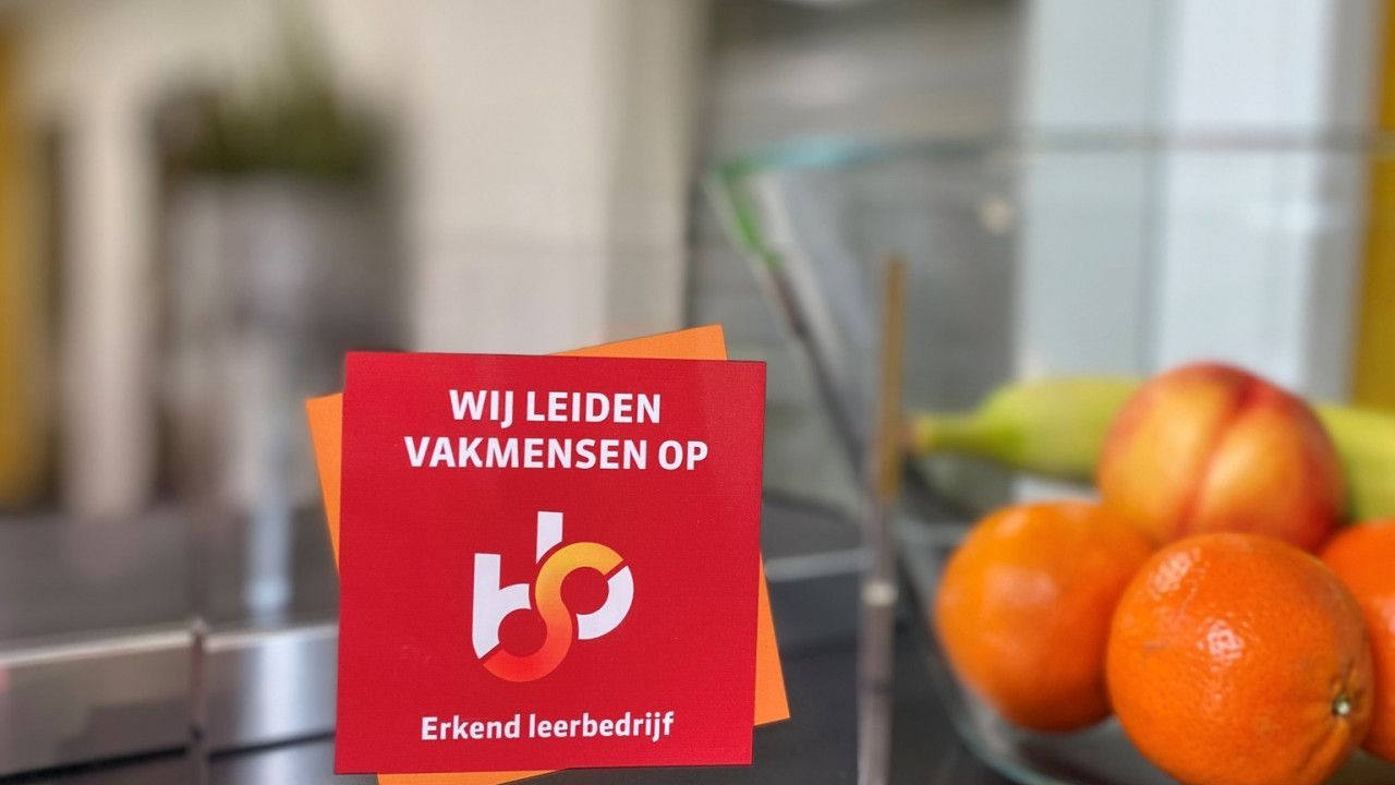 A red sign that says wij leiden vakmensen op