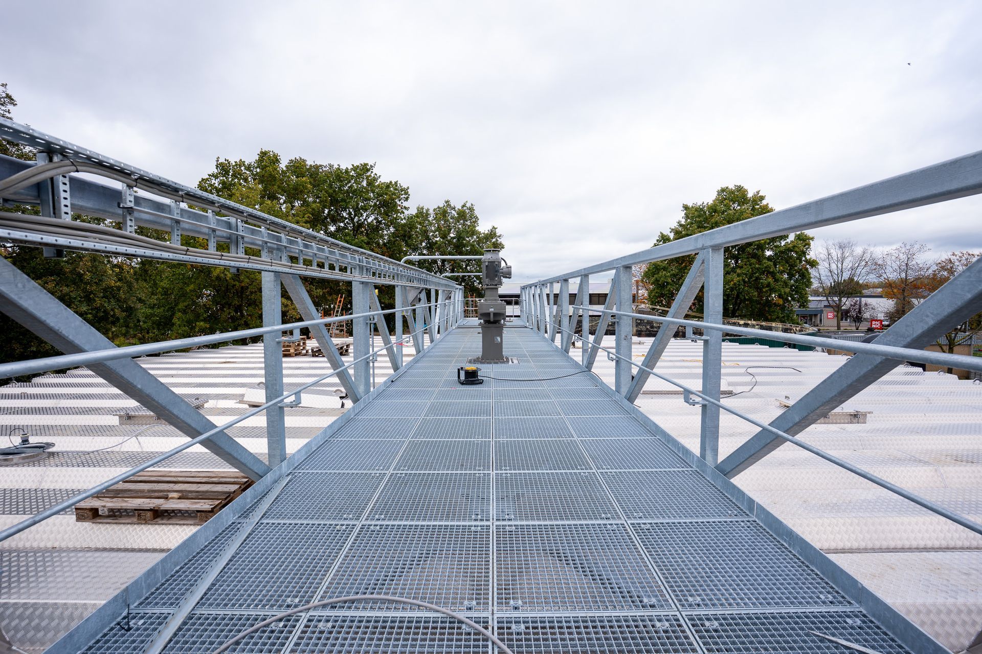 Een stapel gebogen, metalen industriële panelen in een helder verlichte, ruime werkplaats of productiehal.